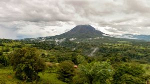 Lush green landscape with a towering, mist-shrouded volcano in the background.